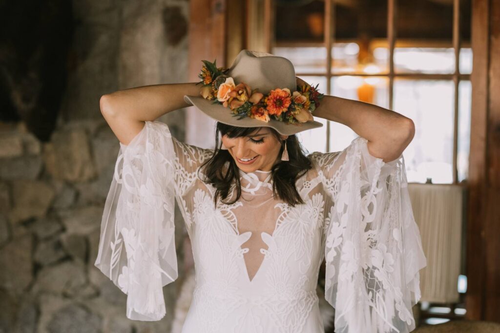 Bride in a boho lacey dress with big sleeves while wearing a floral headband and hat